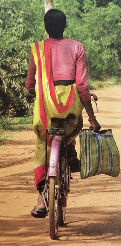 Woman riding a bicyle wearing a sari. Photo from Saris: Tradition and Beyond by 	Rta Kapur Chishti 