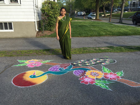 Srivdevi Karthikeyan posing with her finished kolam featuring two peacocks.